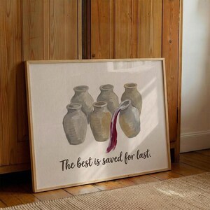 May include: A framed print featuring six beige ceramic jars arranged in a group. One jar on the right is tilted, pouring out a stream of deep red liquid. Below the jars, the text "The best is saved for last." is printed in a dark brown script font.