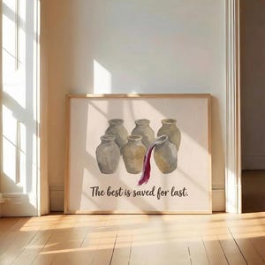 May include: A framed wall art print featuring a painting of six beige ceramic jars arranged in a group. One jar on the right is tilted, pouring out a stream of deep red liquid. The text "The best is saved for last." is printed in black below.