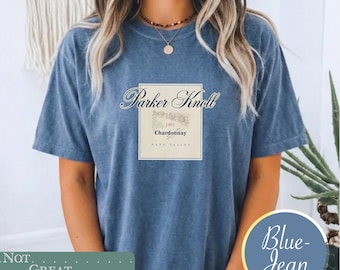 May include: A blue acid-wash t-shirt featuring a rectangular graphic on the chest. The graphic displays the text Parker Knoll above a sketch of a vineyard, the year 1991, the word Chardonnay, and the text Napa Valley in a clean, centered layout.