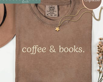 May include: A brown crewneck t-shirt with the text coffee & books. printed in a light cream color on the front. The shirt features a Comfort Colors brand label at the inner neckline and is paired with a gold-toned star pendant necklace.
