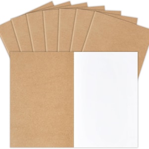 May include: A collection of ten rectangular notebooks arranged in a fan shape. Each notebook features a plain, light brown kraft paper cover. One notebook is positioned in the foreground, open to reveal a blank, white interior page.