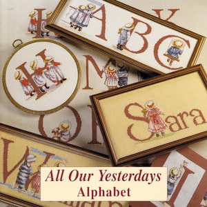 以下が含まれることがあります： 「All Our Yesterdays Alphabet」をテーマにしたクロスステッチ刺繍のコレクション。額装された長方形や円形の刺繍枠のデザインが含まれており、茶色、青、赤の糸で文字や麦わら帽子をかぶった子供たちが表現されています。