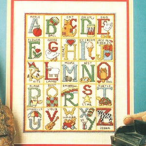 Puede incluir: Una taza de cerámica blanca con un asa negra y el texto "But First, Coffee" en negrita negra. La taza se encuentra sobre un fondo borroso, sugiriendo un ambiente acogedor.