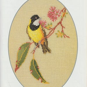 Peut inclure: Un motif de broderie au point de croix sur tissu beige représentant un siffleur doré avec une tête noire, une gorge blanche et une poitrine jaune, perché sur une branche avec des fleurs roses et des feuilles vertes, avec le texte GOLDEN WHISTLER.