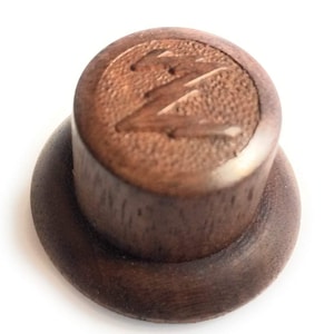 May include: A wooden guitar knob with a carved lightning bolt design. The knob is brown and has a smooth, polished finish.