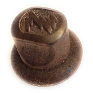 May include: A brown metal bottle cap with a raised "MW" logo.