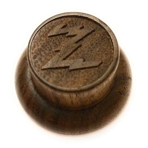 May include: A wooden knob with a stylized lightning bolt design. The knob is dark brown and has a smooth, polished finish.