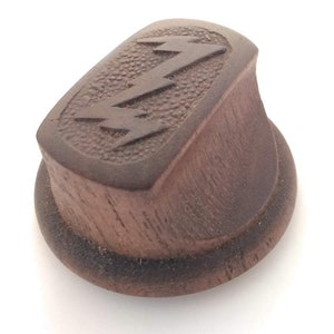 May include: A dark brown wooden knob with a carved lightning bolt design. The knob has a rounded top and a flat base.
