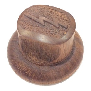 May include: A dark brown wooden knob with a lightning bolt design. The knob has a textured surface and a raised edge.