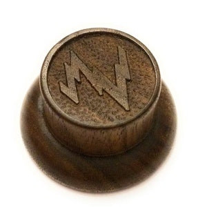 May include: A dark brown wooden guitar knob with a stylised lightning bolt design.