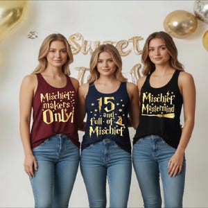May include: Three women wearing tank tops with text. The first tank top is maroon with gold text that reads "Mischief Makers Only". The second tank top is navy blue with gold text that reads "15 and full of Mischief". The third tank top is black with gold text that reads "Mischief Mastermind".