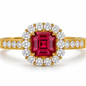 Peut inclure: Une bague en or ornée d'une pierre précieuse rouge foncé de taille carrée au centre, entourée d'un halo de petites pierres blanches rondes. L'anneau est également serti d'une rangée de petites pierres blanches rondes de chaque côté.