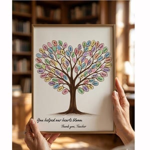 Könnte beinhalten: Gerahmtes Kunstwerk mit einem Baumdesign, dessen Blätter ein Herz bilden, wobei jedes Blatt einen Namen trägt. Der Baumstamm ist braun, und die Blätter sind in Pastelltönen gehalten. Der Text lautet: „You helped our hearts bloom. Thank you, Teacher“.
