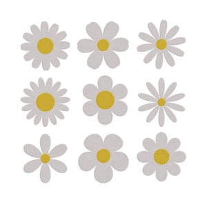 May include: Nine white daisy flower cutouts with yellow centers are arranged on a white background. The flowers have varying petal shapes, some with rounded petals and others with pointed ones. The daisies are a craft or decorative item.