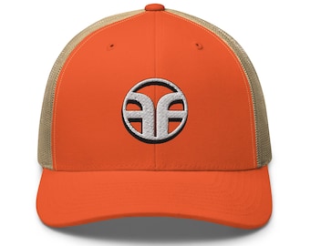Puede incluir: Gorra trucker naranja con un logotipo bordado en blanco y gris. La gorra tiene una parte trasera de malla y una visera curva. El logotipo es un diseño estilizado con forma circular y dos elementos espejados.