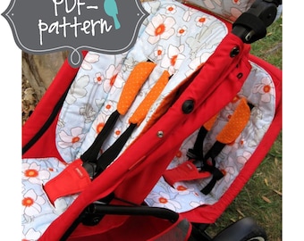 Könnte beinhalten: Ein roter Doppelkinderwagen mit einem Sitzbezug mit Blumenmuster und orangefarbenen Akzenten. Der Kinderwagen hat einen schwarzen Griff und einen schwarzen Netz-Einkaufskorb.