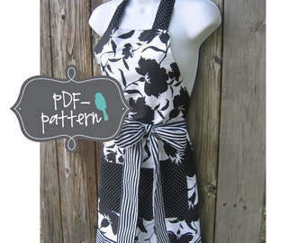 May include: Black and white floral print apron with a black and white striped bow and a black and white polka dot pocket. The apron has a ruffled hem and is hanging on a wooden background. The text "PDF-pattern" is in a gray box with a blue bird.