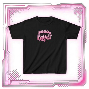 May include: Black t-shirt with the text "2000s Bratz" in a pink gradient font. The shirt has a crew neck and short sleeves. The design is centered on the front of the shirt. The shirt is displayed on a white background.