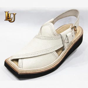 May include: White leather Peshawari sandal with a black sole and a buckle closure. The sandal features a textured leather upper with decorative stitching and a strap around the ankle. The logo "LJ" is in the upper left corner.