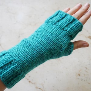 May include: A teal knitted fingerless glove. The glove is made of a soft yarn and features a ribbed cuff and a thumb opening. The knitted texture is visible throughout the glove, offering a cozy and handmade aesthetic.