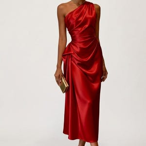 May include: A vibrant red, one-shoulder satin dress with a draped bodice and a fitted waist. The dress falls to a midi length and is paired with matching red heels and a gold clutch. The overall look is elegant and sophisticated.