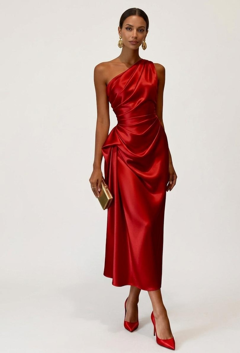 May include: A vibrant red, one-shoulder satin dress with a draped bodice and a fitted waist. The dress falls to a midi length and is paired with matching red heels and a gold clutch. The overall look is elegant and sophisticated.