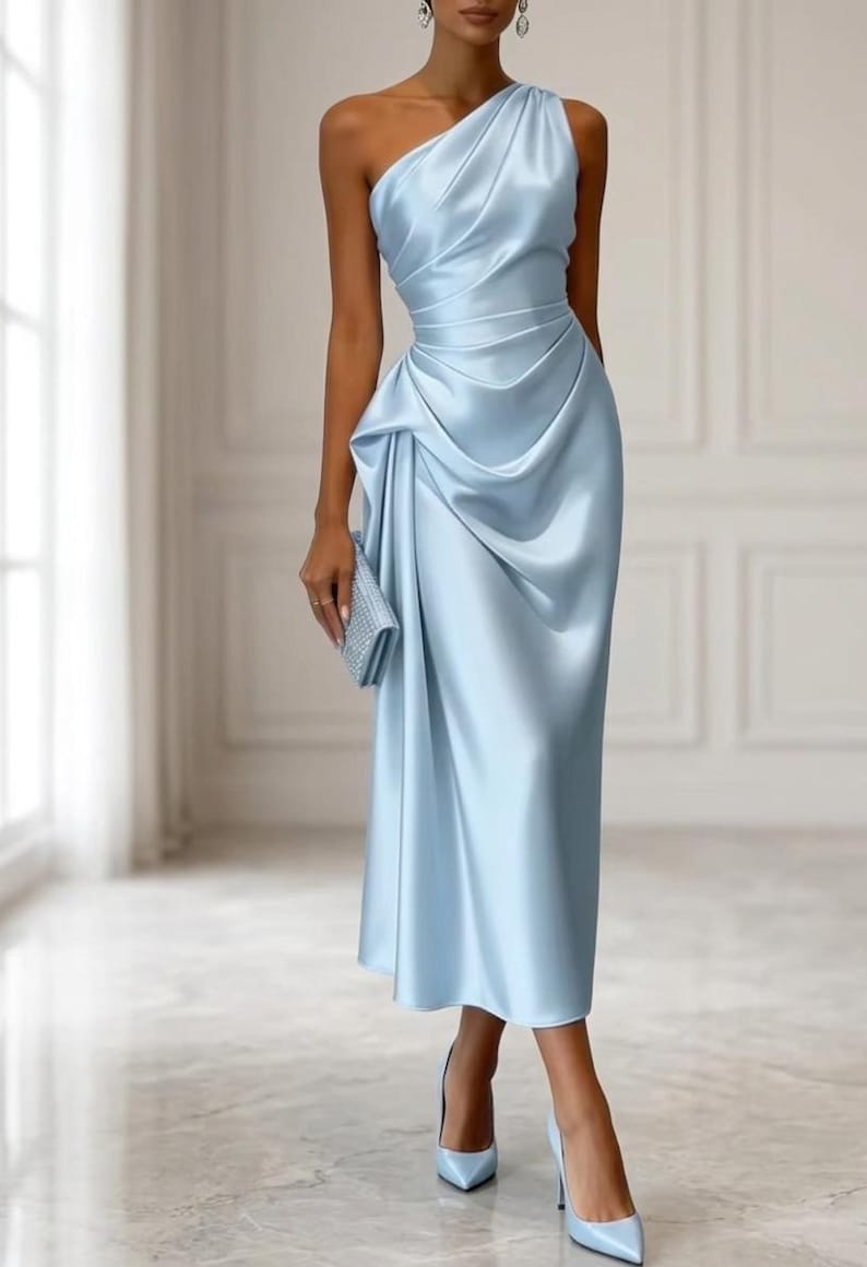 May include: A light blue, one-shoulder satin dress with draped detailing. The dress has a fitted bodice and a knee-length skirt. A matching clutch and heels complete the look. The dress is suitable for formal events.