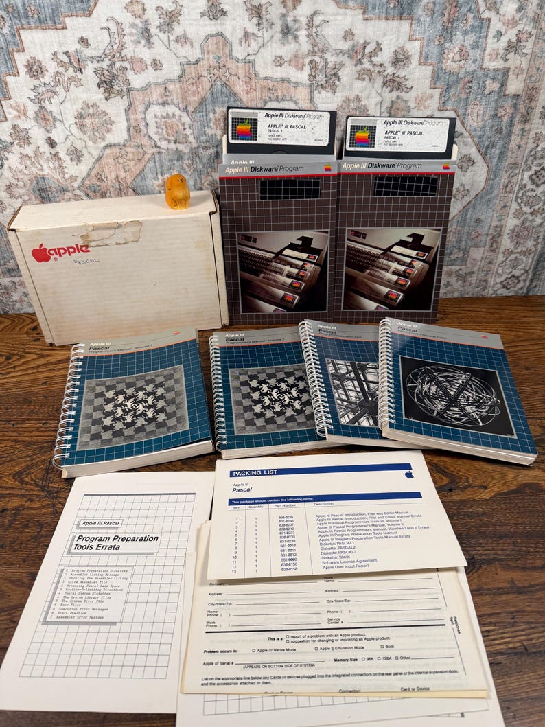 Puede incluir: Una colecci&oacute;n de software Apple III Pascal que incluye dos disquetes en cajas, cuatro manuales encuadernados en espiral con portadas gr&aacute;ficas, una hoja de erratas y una lista de empaque con un formulario de informe de Apple en blanco.