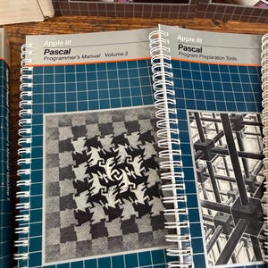 Puede incluir: Dos manuales de Apple III Pascal con encuadernaci&oacute;n en espiral. El manual de la izquierda se titula Apple III Pascal Programmer's Manual Volume 2 con un gr&aacute;fico de lagartos. El de la derecha es Apple III Pascal Program Preparation Tools con un gr&aacute;fico 3D.