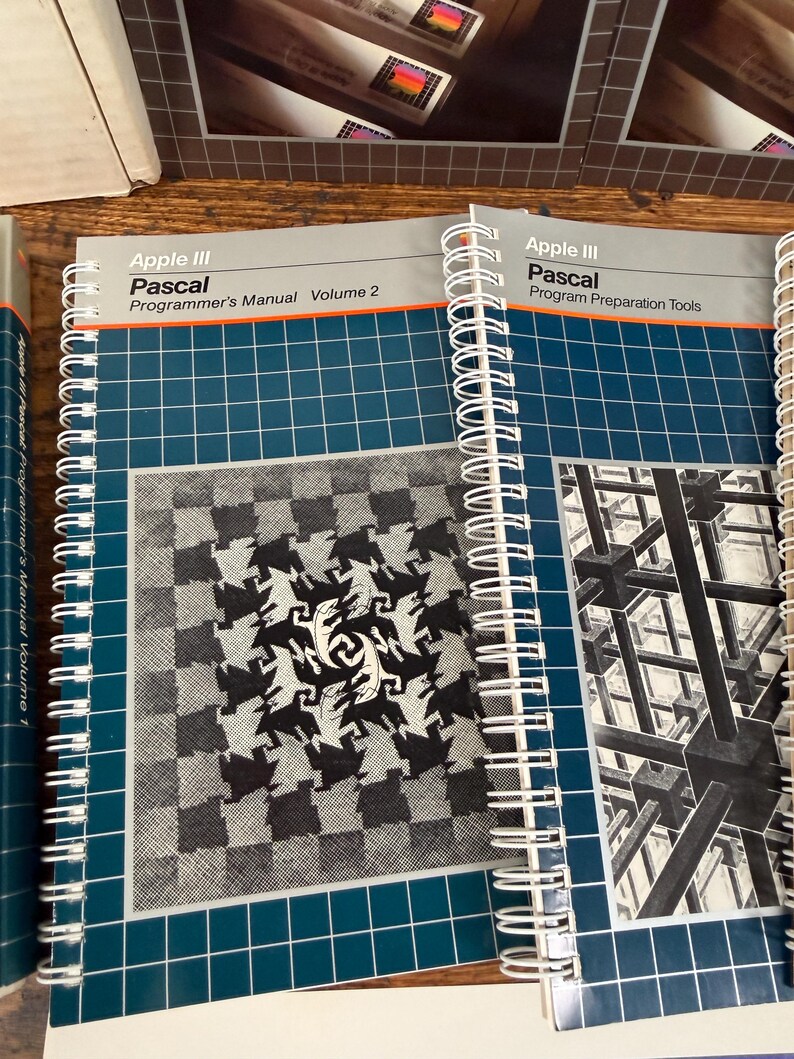 Puede incluir: Dos manuales de Apple III Pascal con encuadernaci&oacute;n en espiral. El manual de la izquierda se titula Apple III Pascal Programmer's Manual Volume 2 con un gr&aacute;fico de lagartos. El de la derecha es Apple III Pascal Program Preparation Tools con un gr&aacute;fico 3D.