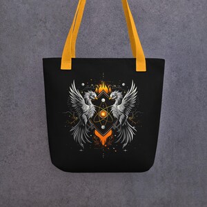 May include: Black tote bag with yellow handles featuring a detailed graphic of two phoenixes facing each other. The design includes an atom symbol, flames, and geometric shapes in orange, white, and gold.