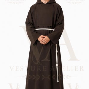 May include: A dark brown full-length robe featuring a hood, long sleeves, and a rectangular chest panel. The garment is cinched at the waist with a white rope belt that includes decorative knots, creating a structured and layered appearance.
