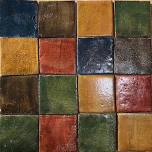 May include: A grid of sixteen square tiles arranged in four rows and four columns. The tiles feature a glossy, textured finish in various earthy tones including deep blue, dark brown, mustard yellow, forest green, and rustic red shades.