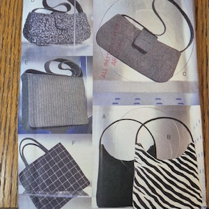 Może przedstawiać: Koperta z wykrojem krawieckim Vogue Accessories o numerze 7328, zawierająca ilustracje sześciu różnych modeli torebek oznaczonych literami od A do F. Wzory obejmują szarą torebkę o fakturze, gładką szarą kopertówkę, torbę na ramię w paski oraz wzór w zebrę.