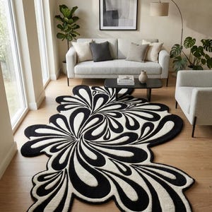 Könnte beinhalten: Ein schwarz-weiß gemusterter Teppich mit einem abstrakten, floralen Design. Das Muster des Teppichs besteht aus wirbelnden, geschwungenen Formen in Schwarz und Weiß. Er liegt auf einem Holzboden in einem Wohnzimmer.