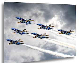 Puede incluir: Fotografía de siete aviones a reacción azules y dorados volando en formación contra un cielo nublado. Los aviones dejan estelas blancas. Los aviones tienen los números del 1 al 7.