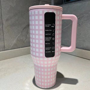 Pu&ograve; includere: Un bicchiere a scacchi rosa e bianco da 1,14 litri con coperchio e manico abbinati. Il bicchiere ha un'etichetta nera con testo che indica caratteristiche come base in gomma, design a prova di perdite e costruzione senza BPA. Mantiene l'acqua fredda fino a 24 ore.
