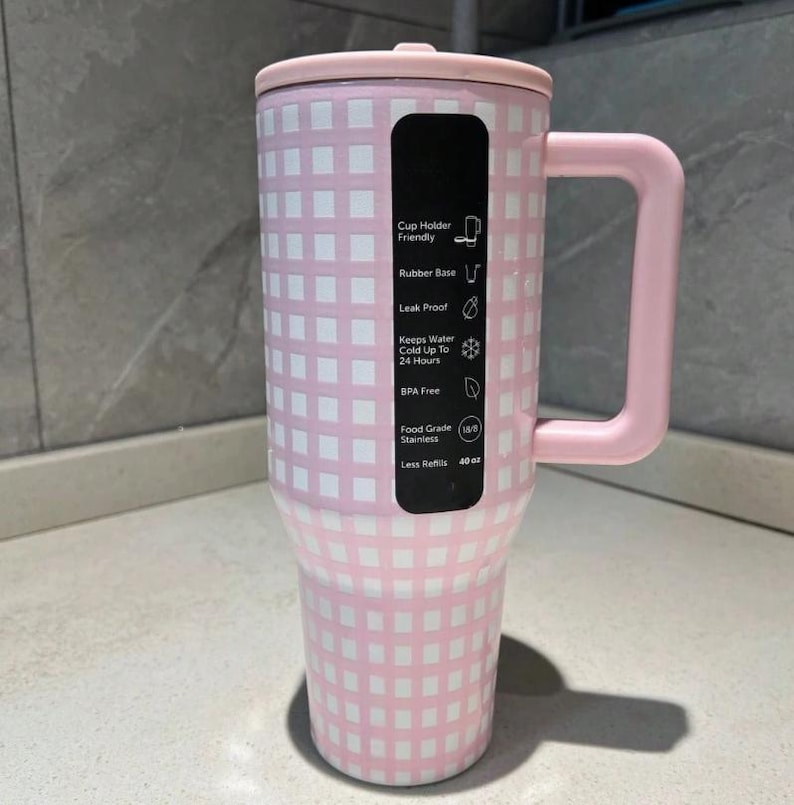 Pu&ograve; includere: Un bicchiere a scacchi rosa e bianco da 1,14 litri con coperchio e manico abbinati. Il bicchiere ha un'etichetta nera con testo che indica caratteristiche come base in gomma, design a prova di perdite e costruzione senza BPA. Mantiene l'acqua fredda fino a 24 ore.