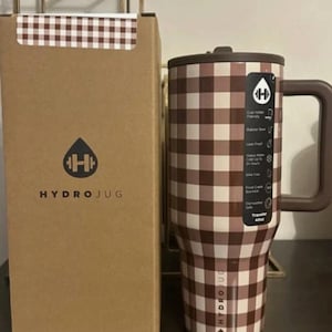 May include: A brown and white checkered Hydrojug tumbler with a handle and a matching box. The tumbler has a brown lid and handle. The box has the Hydrojug logo and text. The tumbler is designed to hold 40oz.