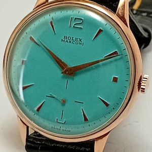 May include: A vintage Rolex Marconi watch with a teal face, gold-tone case, and black leather band. The watch features gold hands and markers, with the number 12 prominently displayed. The words "ROLEX MARCONI" and "SWISS MADE" are visible.
