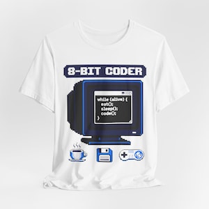Puede incluir: Camiseta blanca con un diseño retro pixelado. El diseño incluye un monitor de ordenador con código, una taza de café, un disquete y un mando de videojuegos. El texto "8-BIT CODER" se muestra encima del monitor.