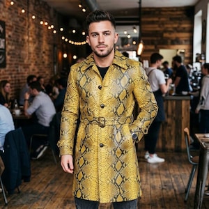 Puede incluir: Una gabardina de manga larga con un vibrante estampado de piel de serpiente en amarillo y negro. El abrigo incluye un cuello clásico, cierre frontal de botones y un cinturón a juego con hebilla en la cintura. Acabado con puños abotonados.