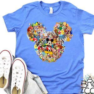 Puede incluir: Camiseta azul claro con un dise&ntilde;o de cabeza de Mickey Mouse compuesto por varios personajes de dibujos animados. Zapatillas blancas y un pantal&oacute;n corto vaquero tambi&eacute;n est&aacute;n en la imagen. El logotipo de Brozco es visible en la esquina inferior derecha.