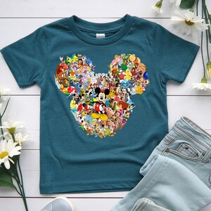 Puede incluir: Camiseta de color turquesa con un dise&ntilde;o de cabeza de Mickey Mouse lleno de varios personajes de Disney. El gr&aacute;fico incluye a Mickey Mouse en el centro, rodeado de personajes de pel&iacute;culas de Disney. La camiseta se combina con vaqueros de mezclilla azul claro.
