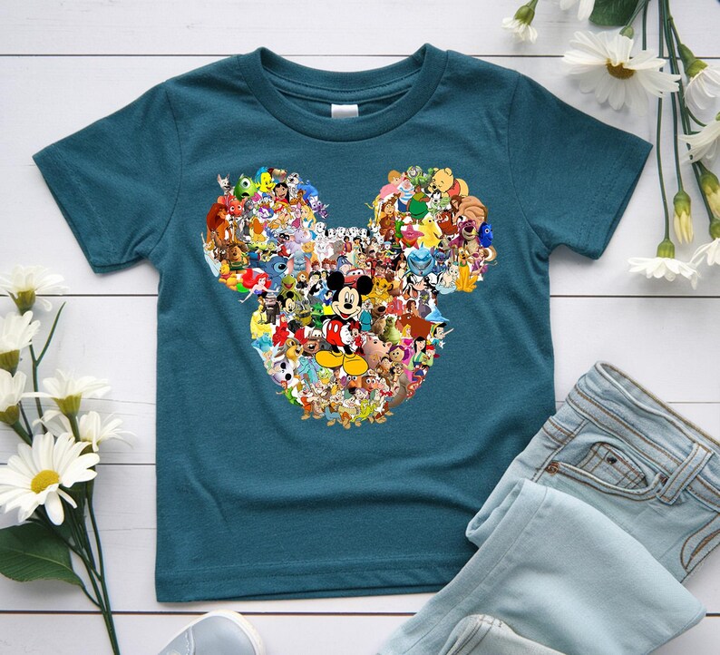 Puede incluir: Camiseta de color turquesa con un dise&ntilde;o de cabeza de Mickey Mouse lleno de varios personajes de Disney. El gr&aacute;fico incluye a Mickey Mouse en el centro, rodeado de personajes de pel&iacute;culas de Disney. La camiseta se combina con vaqueros de mezclilla azul claro.