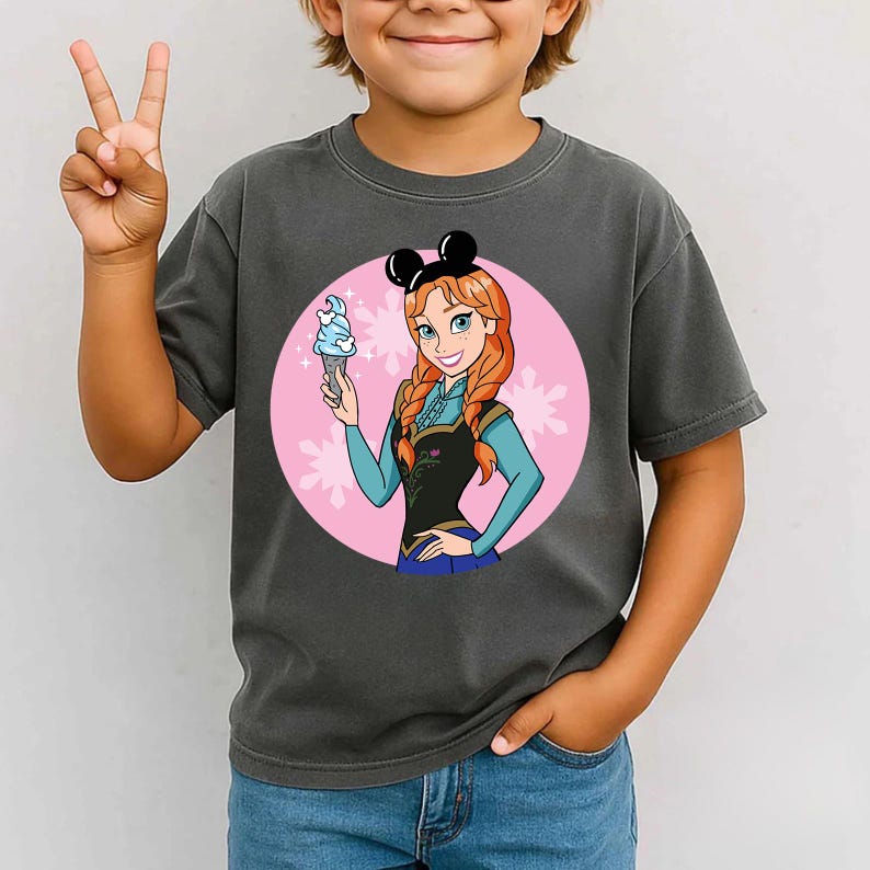 May include: Dark gray t-shirt featuring a cartoon image of a character holding an ice cream cone. The character has red hair and is wearing a black top and blue sleeves. The image is set against a pink circle with white snowflake accents.