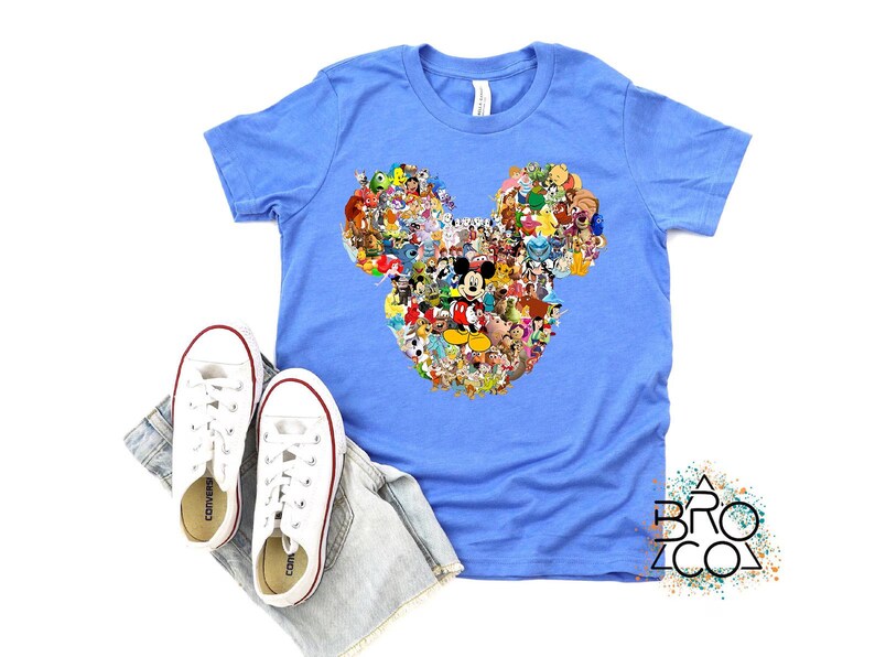 Puede incluir: Camiseta azul claro con un dise&ntilde;o de cabeza de Mickey Mouse compuesto por varios personajes de dibujos animados. Zapatillas blancas y un pantal&oacute;n corto vaquero tambi&eacute;n est&aacute;n en la imagen. El logotipo de Brozco es visible en la esquina inferior derecha.