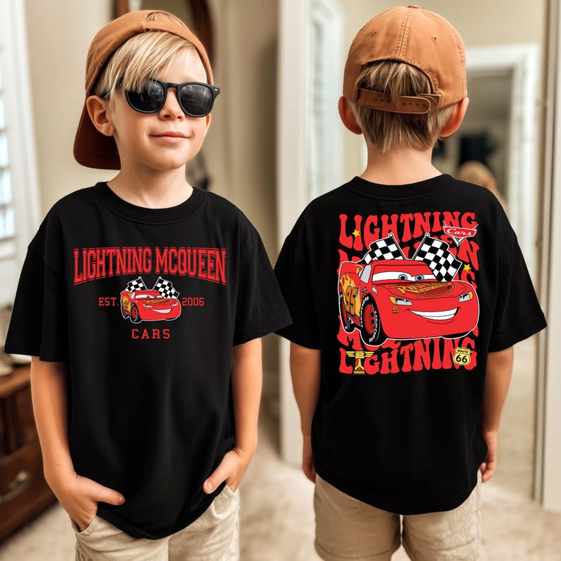 May include: Black Lightning McQueen t-shirt with a red and white graphic of the character from the Cars movie. The front of the shirt has the text "Lightning McQueen" and "Cars". The back of the shirt has a larger graphic of Lightning McQueen.