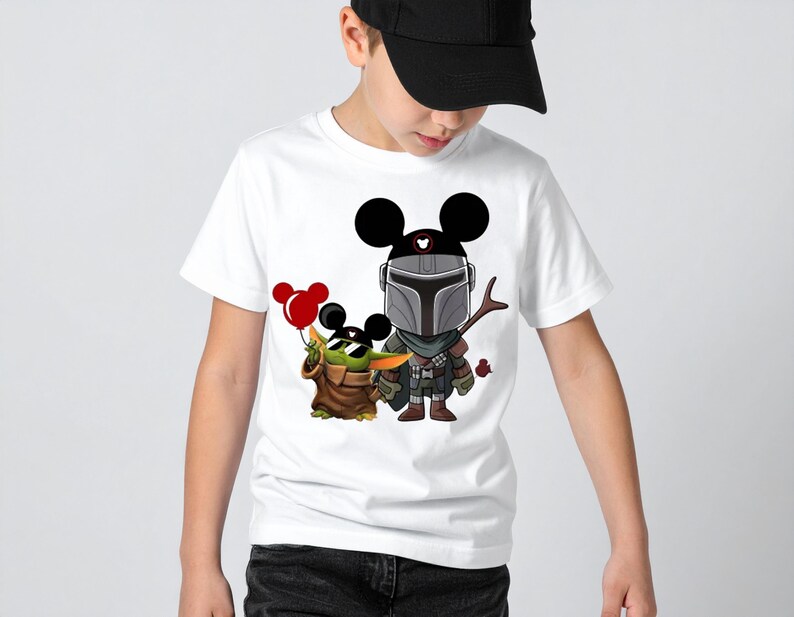 May include: White t-shirt featuring a cartoon illustration of The Mandalorian and Grogu, with Mickey Mouse ears. Grogu is holding red balloons. The Mandalorian is holding a spear. The shirt is worn by a person.