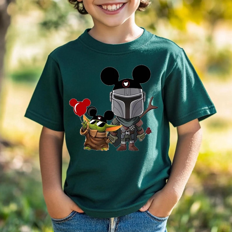 May include: Dark green t-shirt featuring a cartoon illustration of Mickey Mouse characters as The Mandalorian and Grogu. Grogu is wearing sunglasses and holding a red balloon. The Mandalorian is holding a rose.